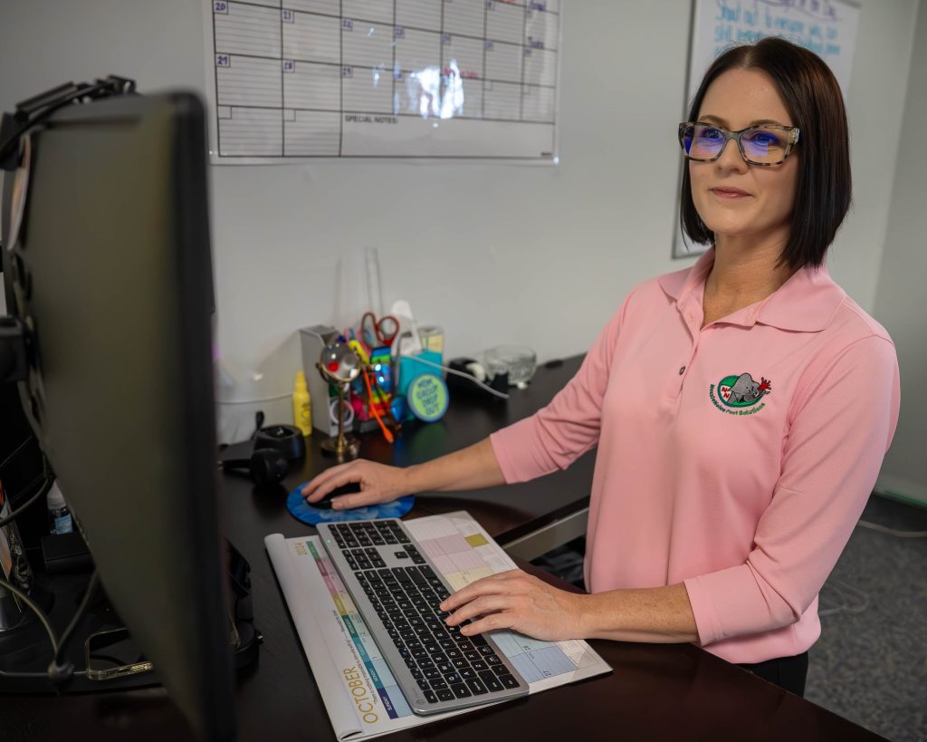 A pest control team member working at a desk, managing schedules and tasks on a computer.