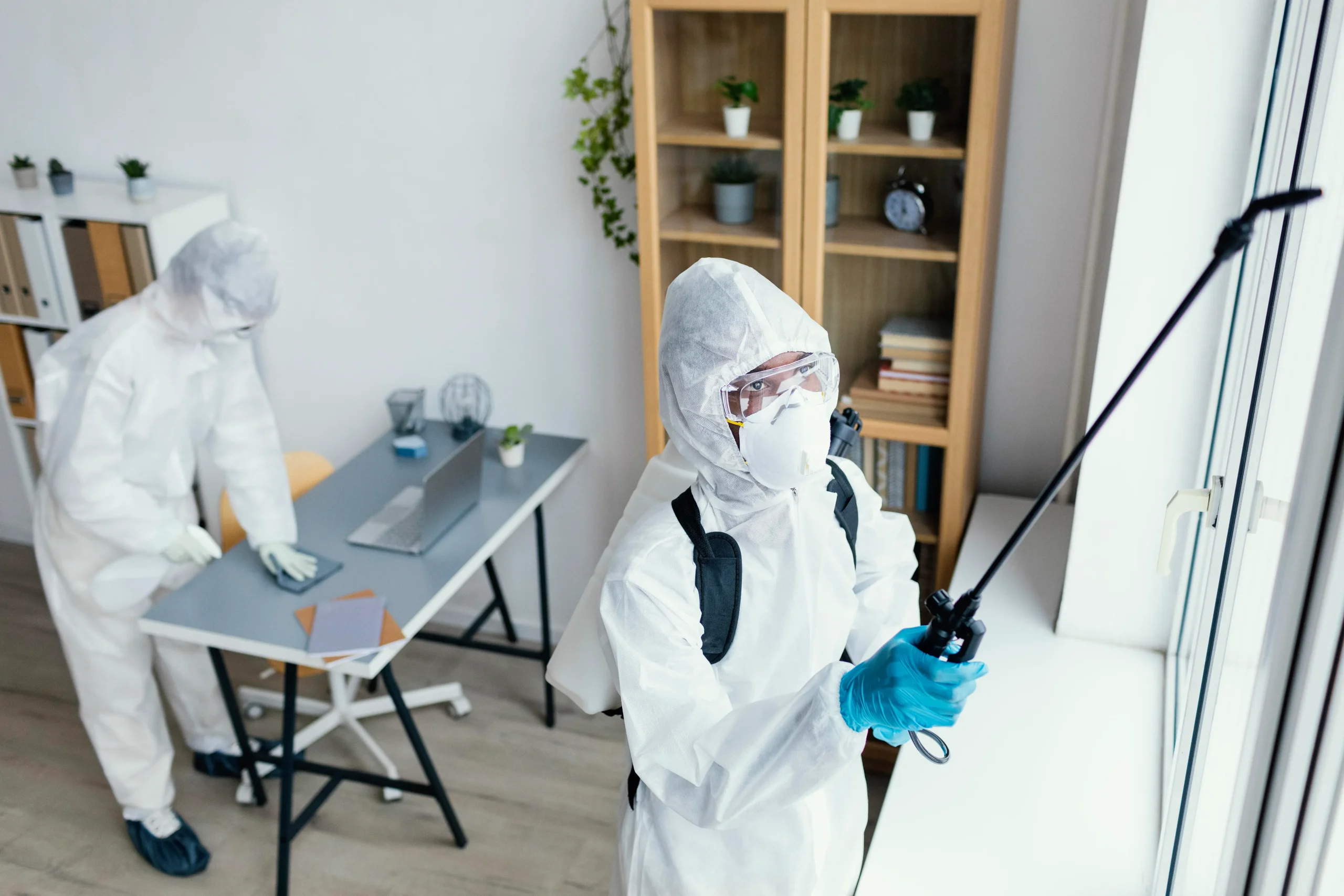 Pest control workers in protective suits treating an office space