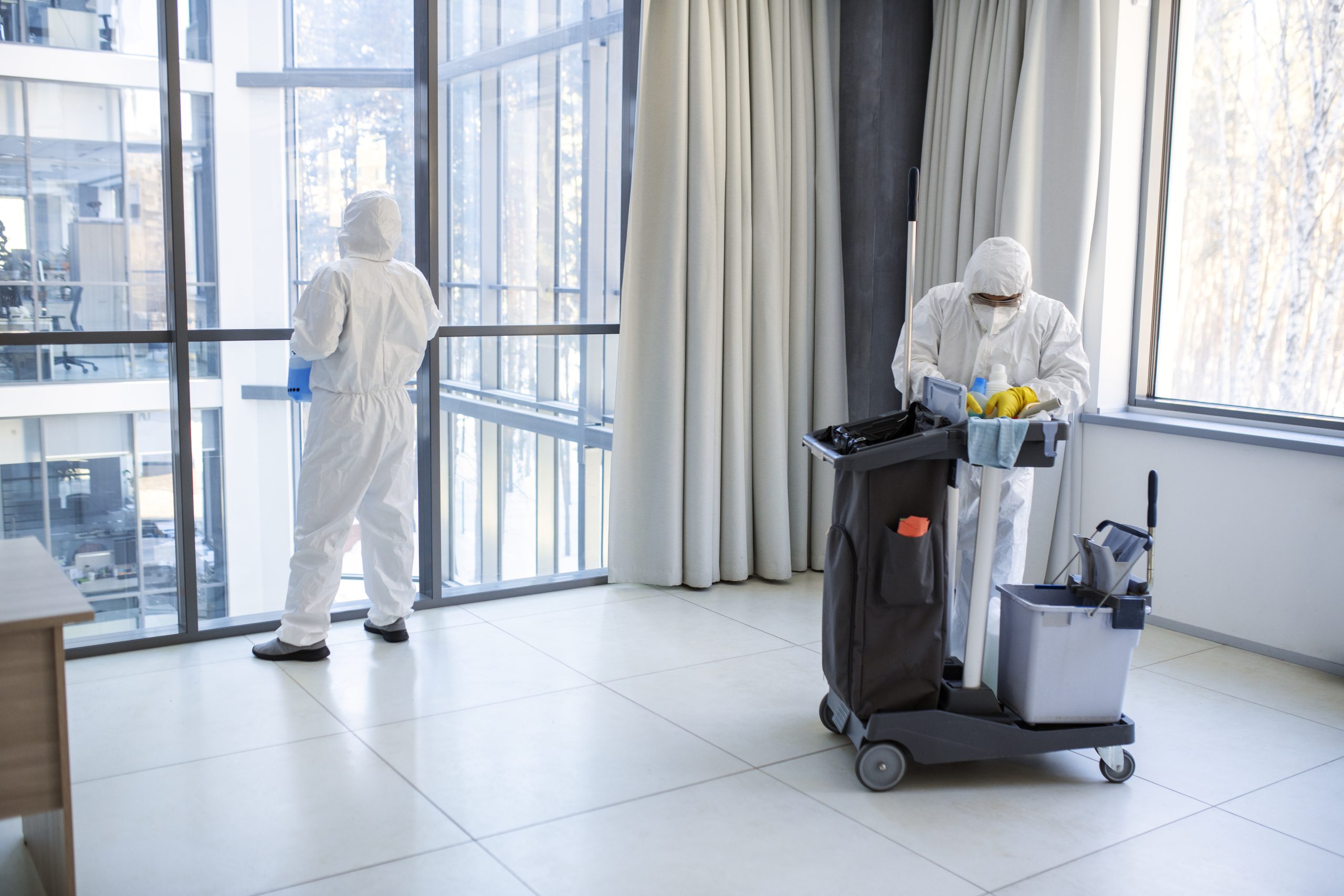 Two pest control technicians in hazmat suits with cleaning cart inspecting a hotel room – hospitality pest control services