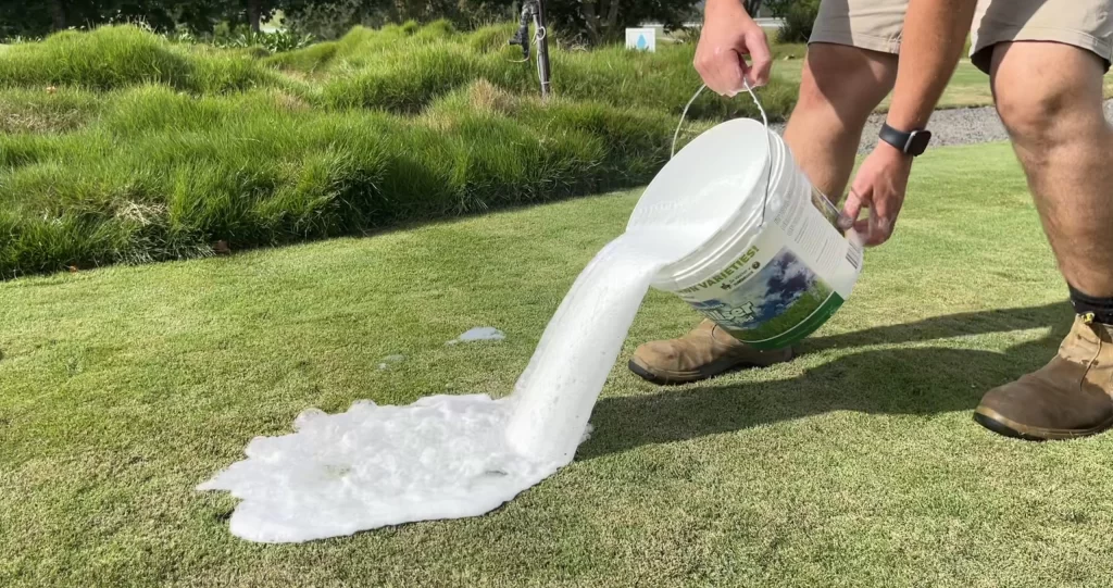 Lawn care treatment being poured onto healthy grass