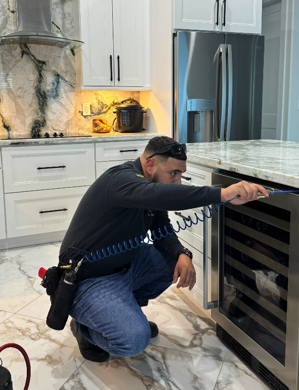 Technician inspecting kitchen appliance for pests.